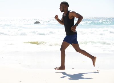 fit man running barefoot on beach