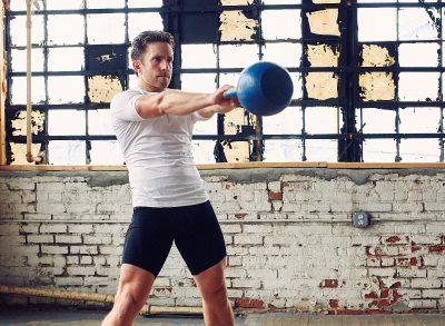 man doing kettlebell workout in gym