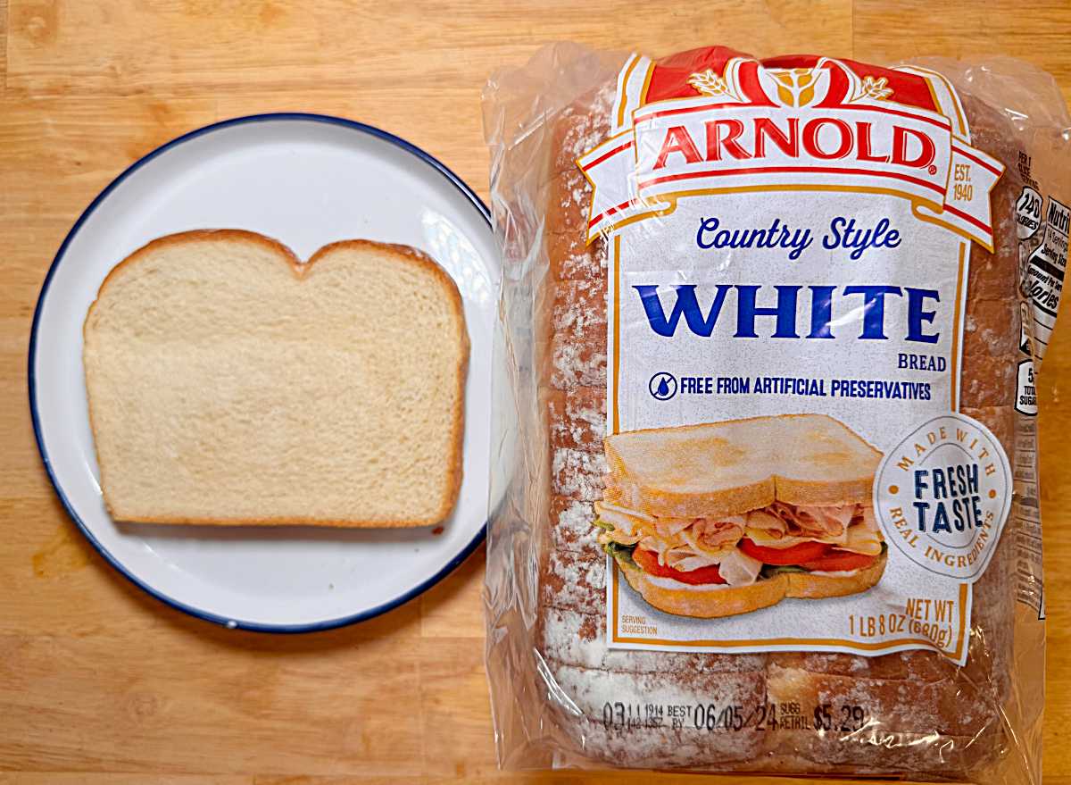 a loaf of country white bread next to a slice on a plate