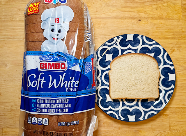 a loaf of bimbo soft white bread next to a slice on a printed plate 