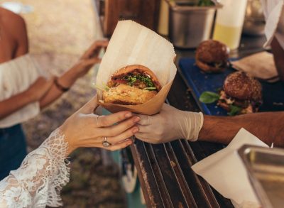 man hands delicious burger to woman