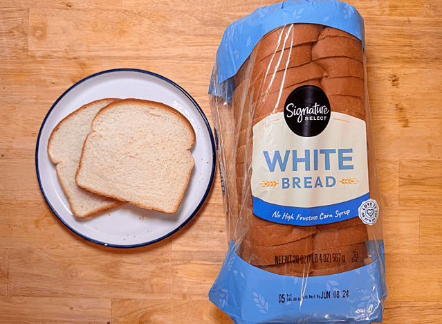 a loaf of signature select white bread with two slices on a plate 
