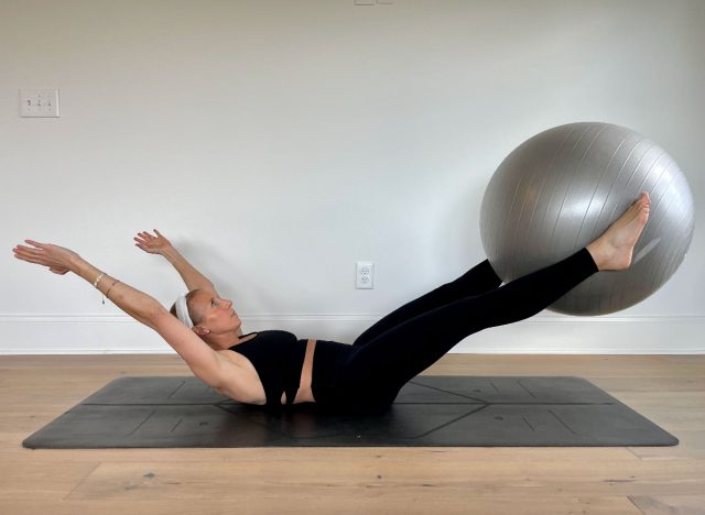 trainer demonstrating the v-pass stability ball exercise to reduce abdominal fat