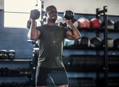 man doing dumbbell press exercise to burn fat in midsection