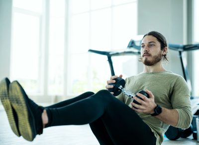 man performing dumbbell crunches in bright gym to get rid of belly creases