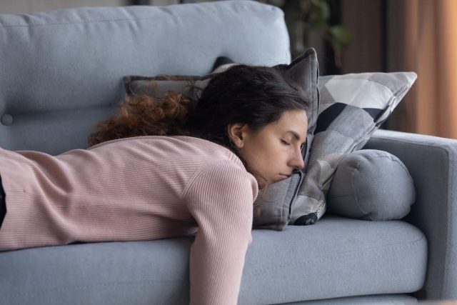 tired woman falling asleep on couch