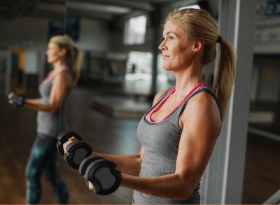 woman doing dumbbell exercise to get rid of bat wings for good