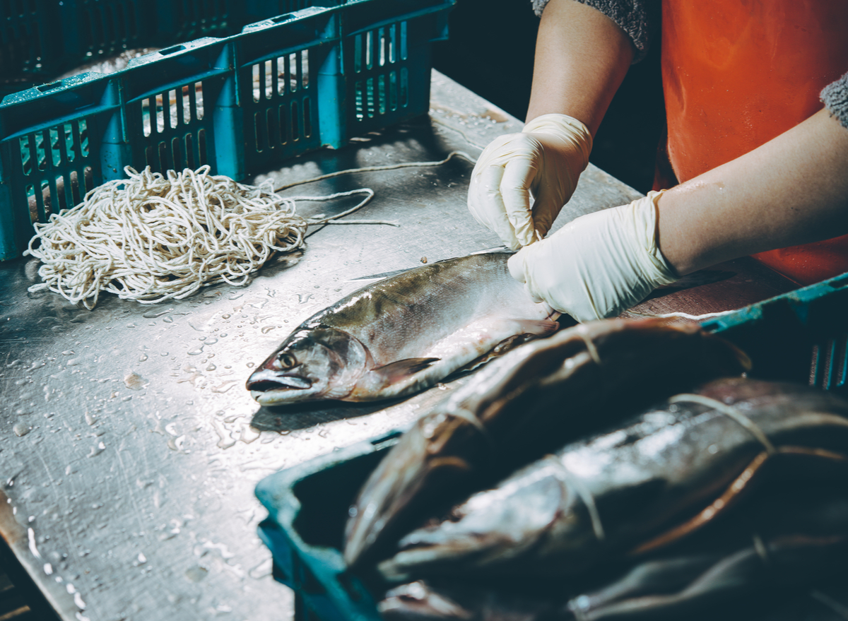 https://www.eatthis.com/wp-content/uploads/sites/4/2022/06/worker-holding-fish-factory.jpg?quality=82&strip=1