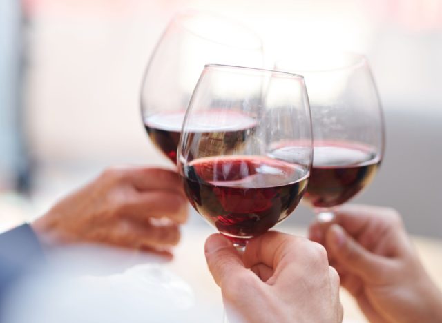 three people holding red wine glasses