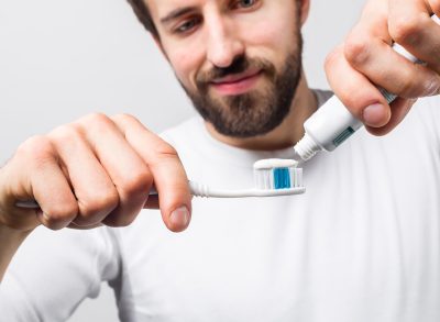 man putting toothpaste on his toothbrush, side effects of not brushing teeth at night