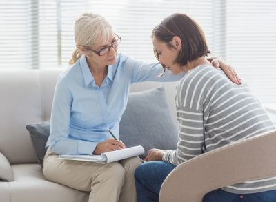 mature therapist helping female patient regarding how to deal with losing a parent