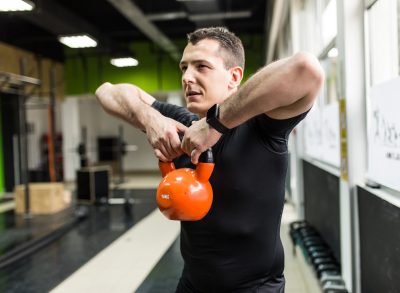 man demonstrating kettlebell workout to get rid of your belly overhang