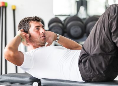 mature man doing sit-ups to shrink a big belly for good