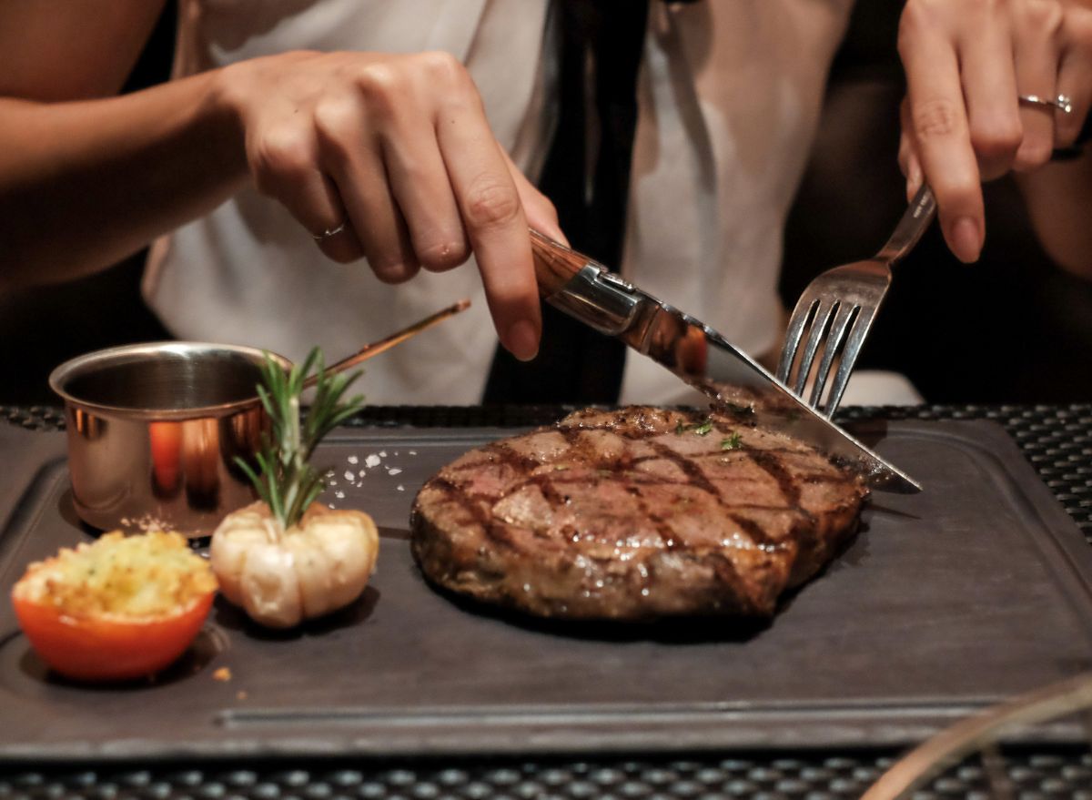 https://www.eatthis.com/wp-content/uploads/sites/4/2022/10/Eating-a-steak.jpg?quality=82&strip=1