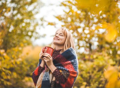 happy woman holding coffee mug, demonstrating the one daily habit to extend your life