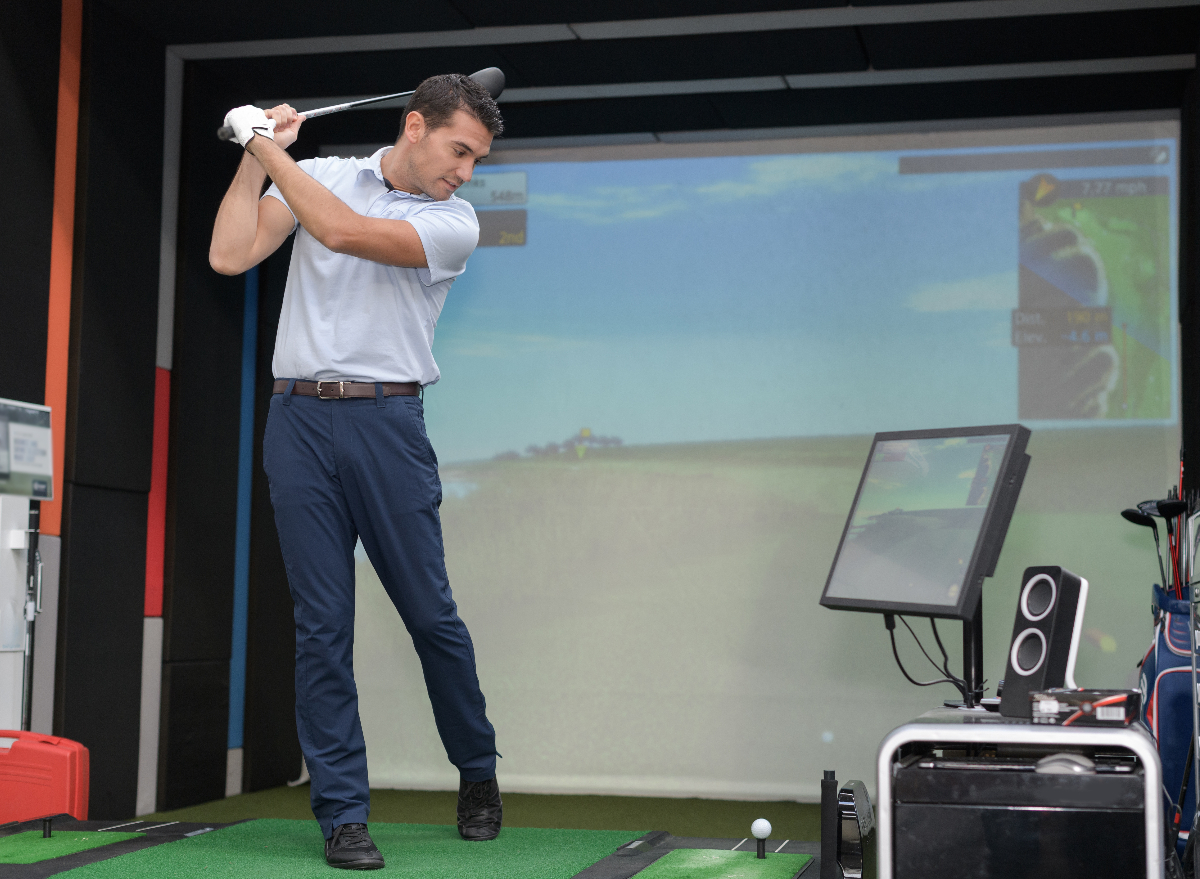 man golfing on golf simulator