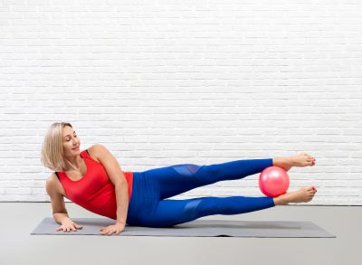 woman exercising with a pilates ball, performing pilates workout for better sex