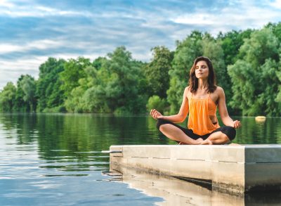 woman practicing yoga on lake to achieve wellness goals