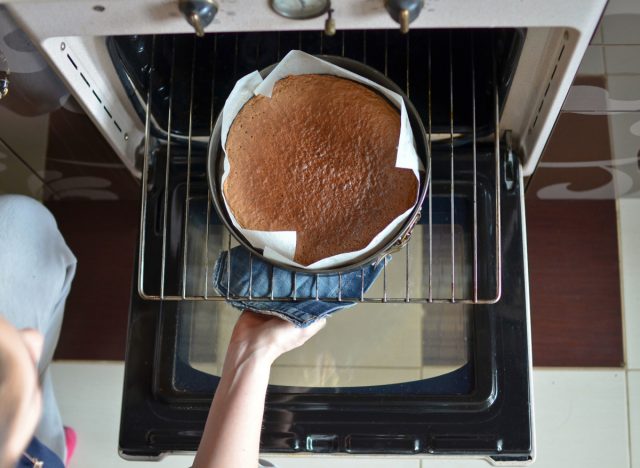 woman taking cake out of the oven