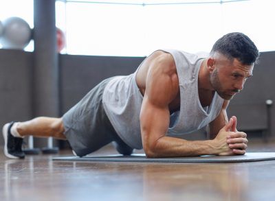 fitness man performing forearm plank exercise to melt winter gut