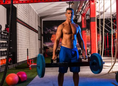 middle-aged man holding hex bar performing strength exercises at the gym