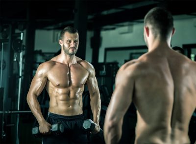 muscular man holding dumbbells, concept of workout to build strength