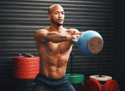 fit man doing kettlebell swings, concept of body recomposition exercises