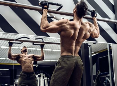 muscular man at the gym doing workout for V-taper back, pull-ups