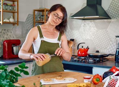 woman making nut butter breakfast, concept of breakfast habits for women to lose belly fat