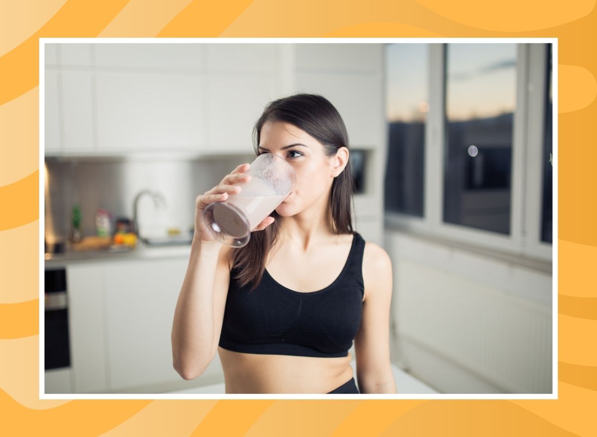 woman drinking a shake out of a glass on an orange background