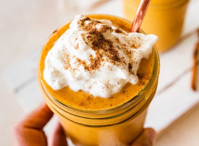 person holding a pumpkin protein shake in a glass