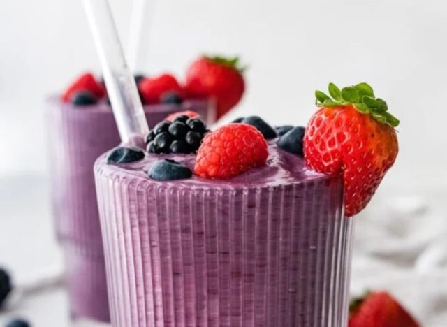 two smoothie glasses with berries on top and a straw