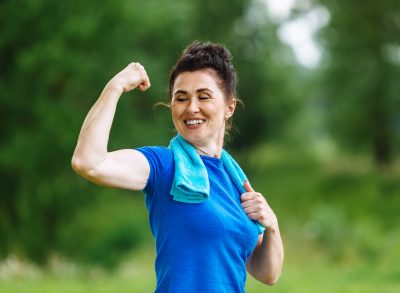 fit mature woman flexing, concept of exercise habits for women to get firm and lean after 50