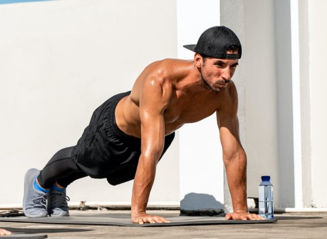 fit muscular man doing pushups, high plank position, concept of daily floor exercises for men to stay fit