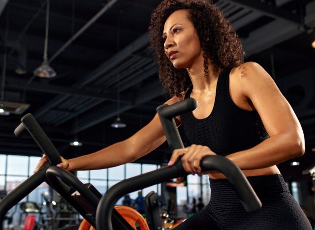 woman doing air bike at gym, concept of best belly fat exercises to do at gym