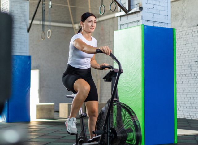 Woman riding air bike, machine concept for weight loss