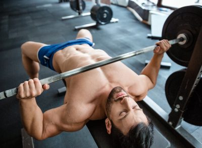 fit man doing barbell bench press exercise, concept of strength exercises for men in their 30s