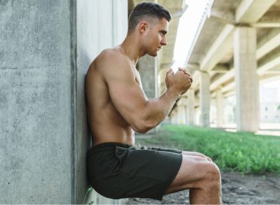 man doing wall sits, concept of how out of shape are you test from a trainer