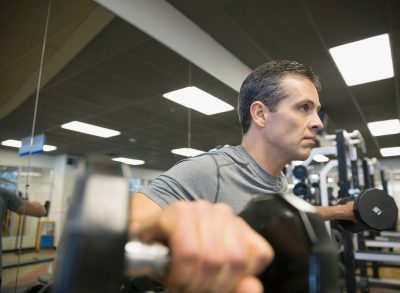 fit man doing standing exercises to boost muscular endurance after 50 with dumbbells