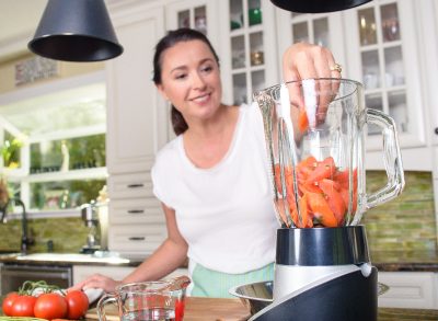 woman putting veggies in blender, concept of things women should do for hormonal health in their 40s