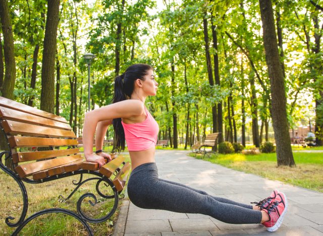 femme faisant des trempettes de triceps sur un banc à l'extérieur, concept d'exercices pour les femmes pour tonifier les aisselles