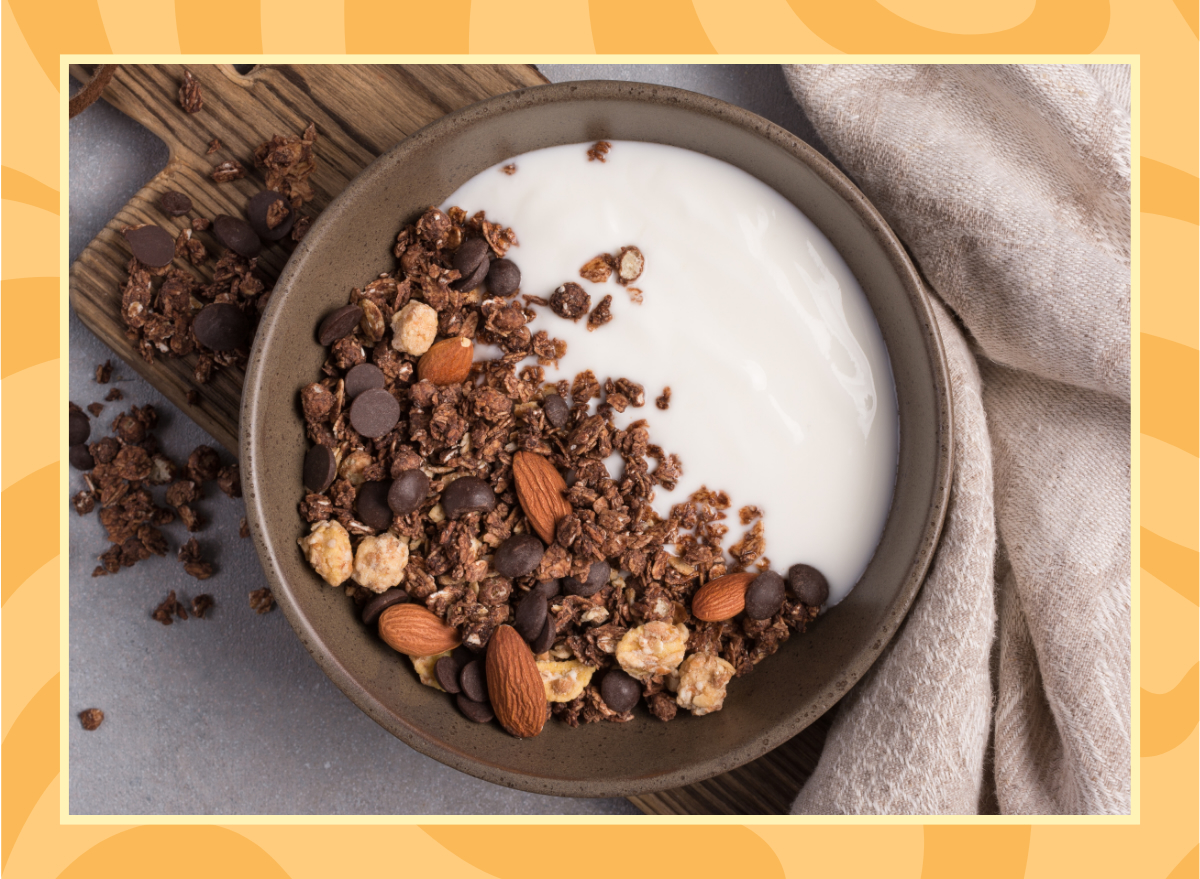 Top view of granola with yogurt, chocolate drops and almond nuts for healthy breakfast on grey concrete background