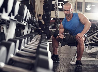 man lifting weights at gym, concept of quick muscle-building tips for guys