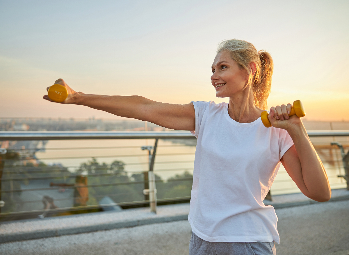 Confident muscular woman flexing muscles while standing in park