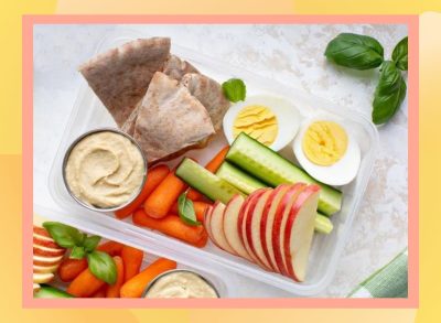 a photo of a high-protein snack plate with apples, carrots, eggs, hummus on a designed background