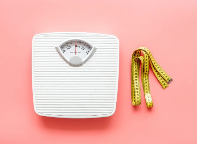 Scales and measuring tape on pink background. Weight loss concept