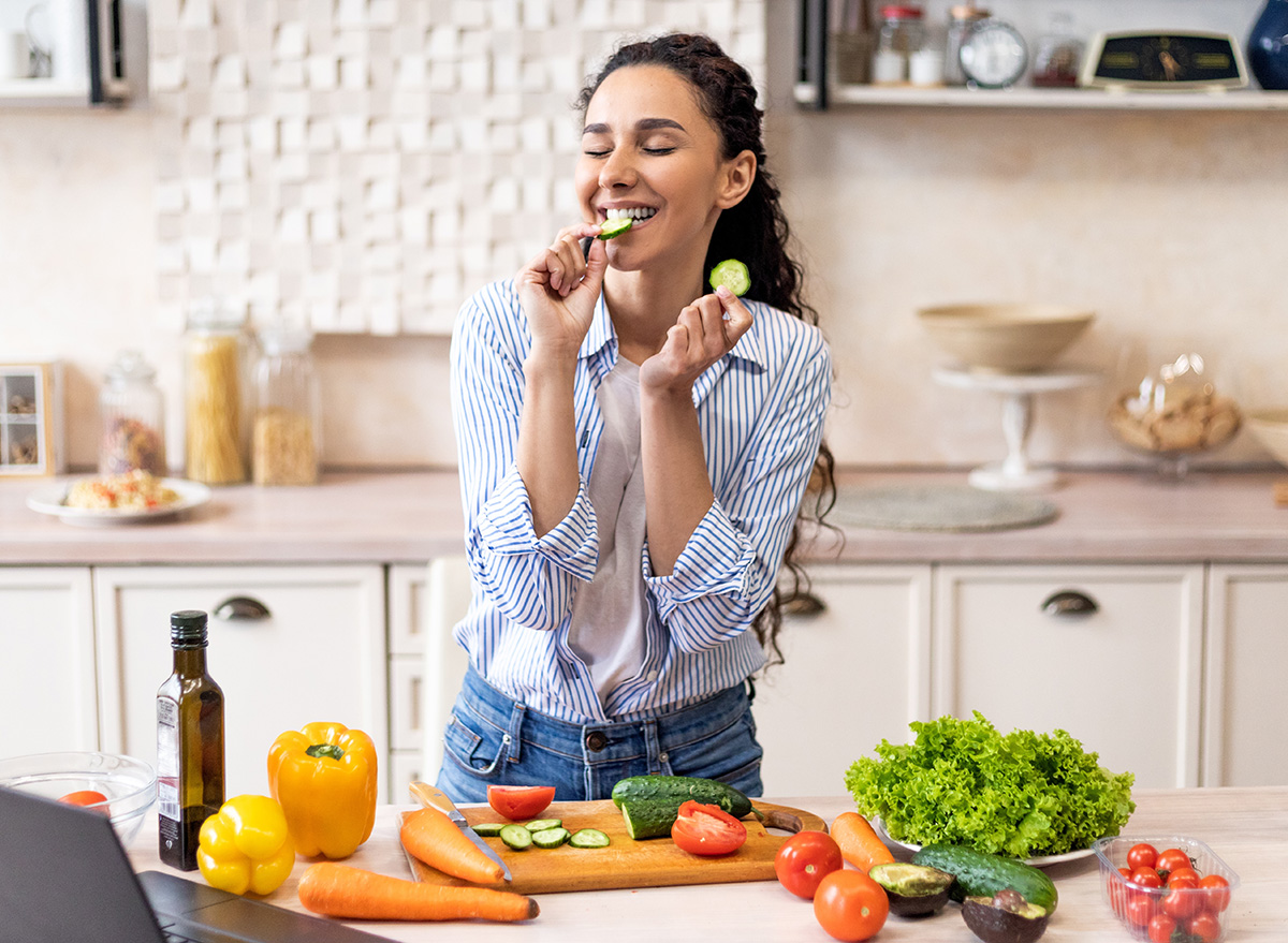 Young,Latin,Woman,Cooking,Fresh,Vegetable,Salad,And,Biting,Cucumber,