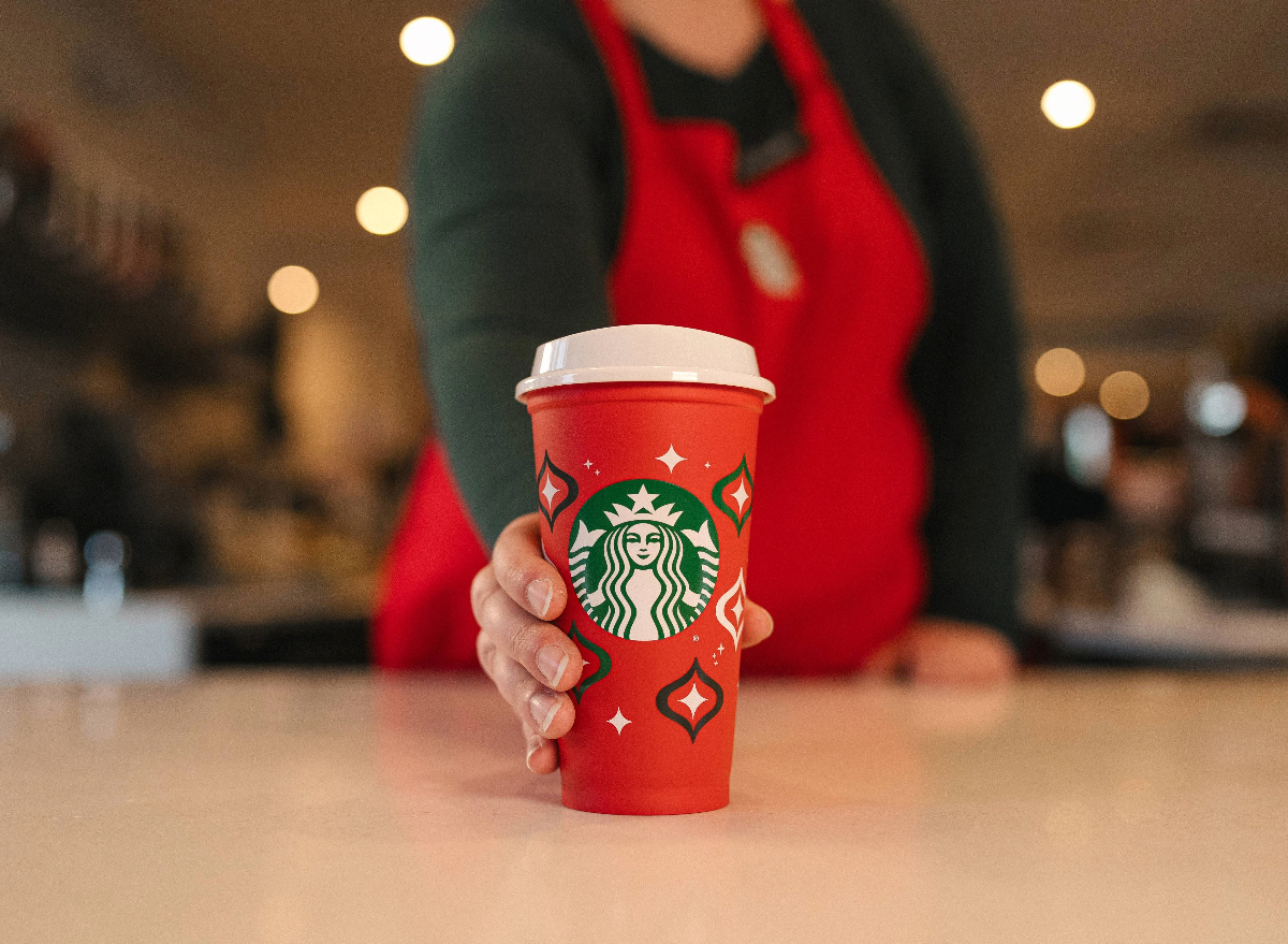 https://www.eatthis.com/wp-content/uploads/sites/4/2023/11/starbucks-employee-holding-reusable-red-cup.jpeg?quality=82&strip=1
