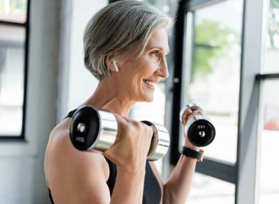 happy woman lifting weights, concept of how many days a week to exercise for results