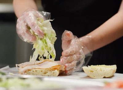 Port of Subs worker assembling a sandwich